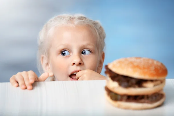 Zabawna dziewczyna trochę patrząc na burger — Zdjęcie stockowe