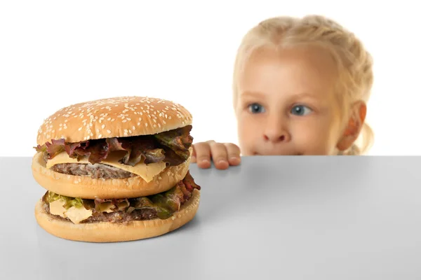 Menina engraçada olhando no hambúrguer grande — Fotografia de Stock