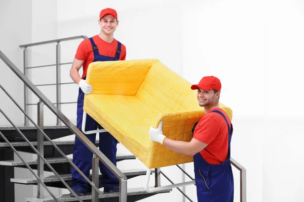 Dos trabajadores masculinos con sofá amarillo — Foto de Stock