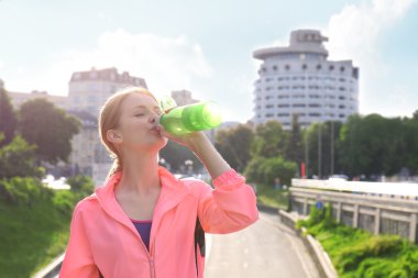Kadın koşudan sonra su içiyor.  