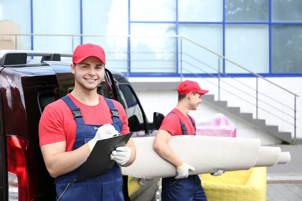 Twee mannelijke werknemers lossen tapijt — Stockfoto