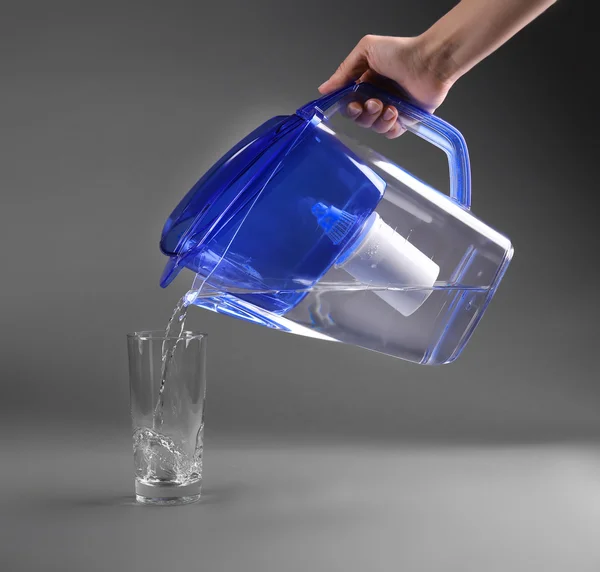Frauenhand gießt Wasser ins Glas — Stockfoto