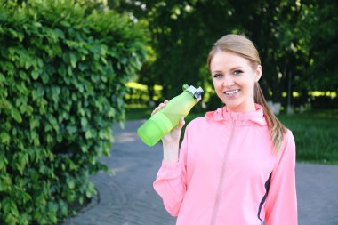 Kadın koşudan sonra su içiyor. 