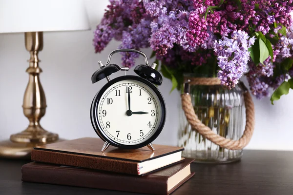 Alarm clock with lilac bouquet — Stock Photo, Image