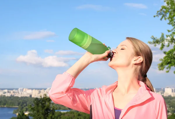 Mulher desportiva beber água depois de correr em um dia ensolarado — Fotografia de Stock