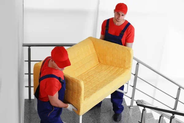 Dos trabajadores masculinos con sofá amarillo —  Fotos de Stock