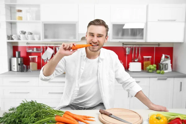 Bello uomo mangiare carota — Foto Stock