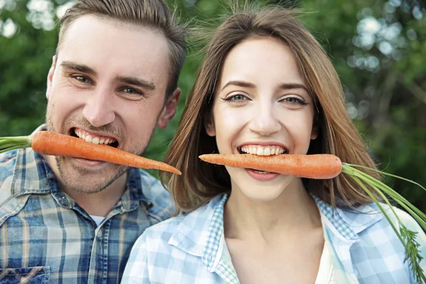 Hombre guapo y hermosa chica comiendo zanahorias, primer plano —  Fotos de Stock