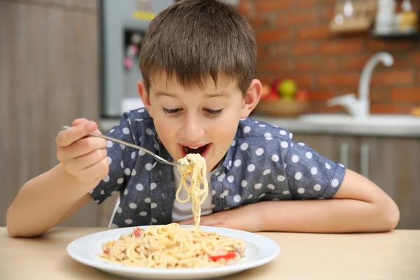Cute boy eating spaghetti