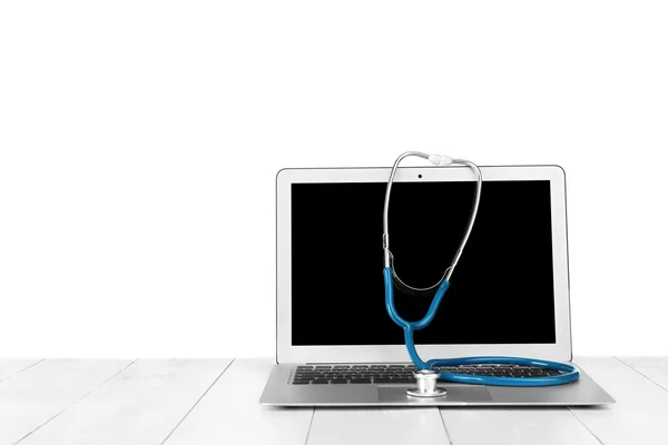 Laptop with stethoscope on table — Stock Photo, Image