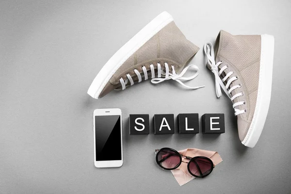 Сіре взуття, сонцезахисні окуляри та мобільний телефон — стокове фото