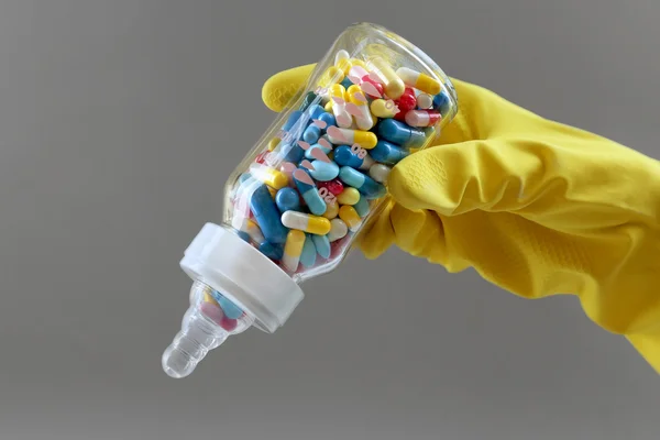 Mão segurando garrafa de alimentação cheia de pílulas — Fotografia de Stock