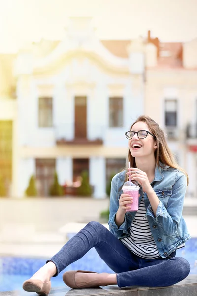 Привлекательная женщина сидит на фонтане с фруктовым коктейлем — стоковое фото