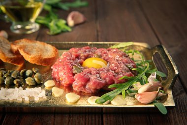 Biftek tartar kıyılmış onio ve bir tepsi üzerinde turşu ile