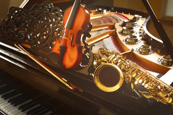 Fiol och saxofon liggande på piano — Stockfoto
