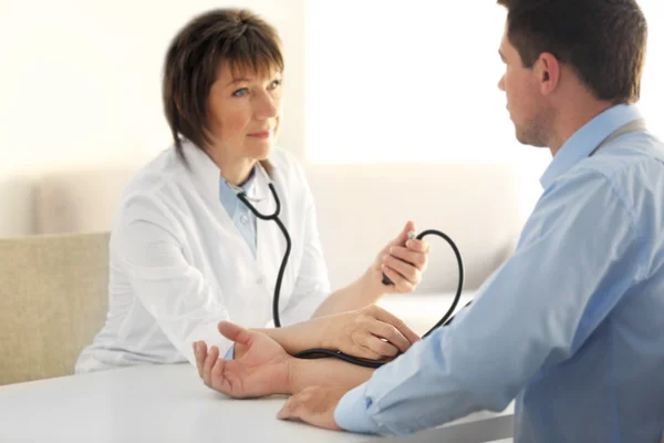 女医生与眼压计测量人的血压 — 图库照片