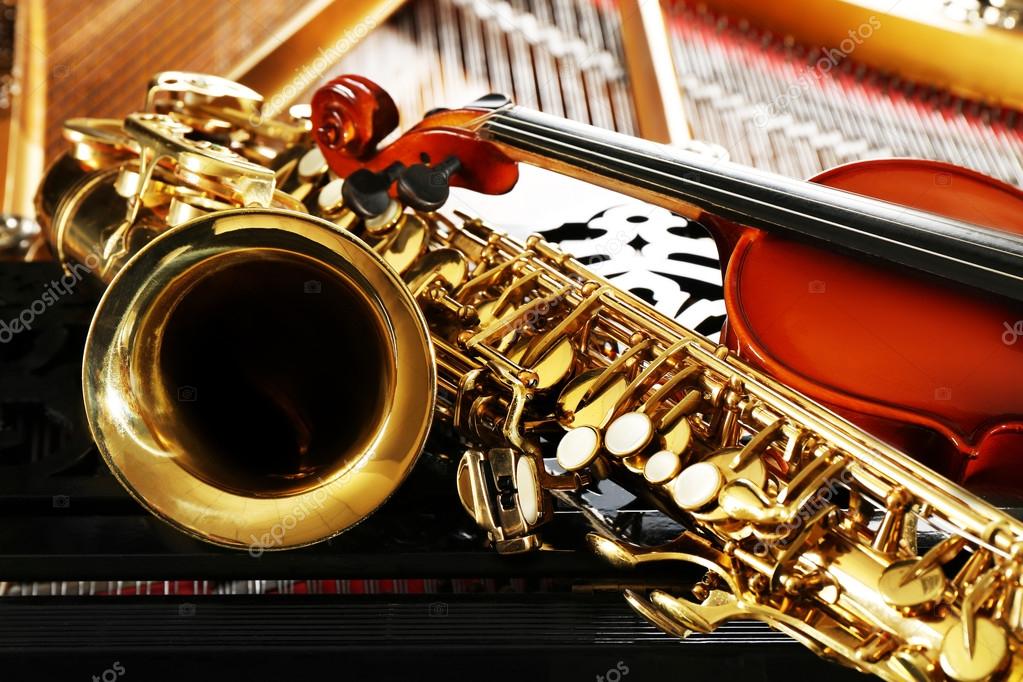 Violin and saxophone lying on piano — Stock Photo © belchonock 117725598