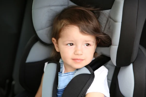 Menino sentado em um carro em cadeira de segurança — Fotografia de Stock