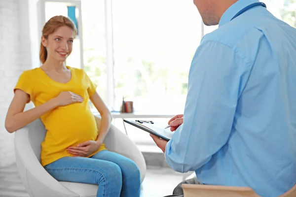 Беременная молодая женщина, посещающая врача — стоковое фото