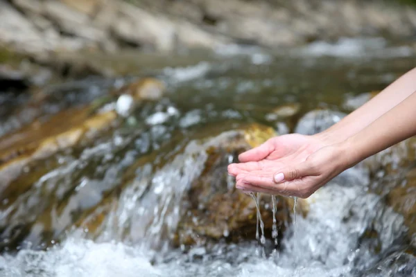 Female hand in water stream