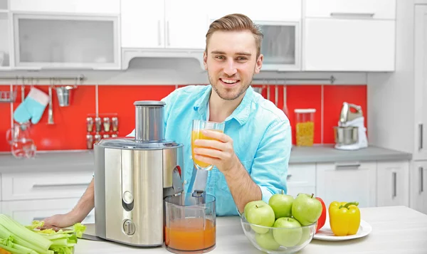 Homem com suco na cozinha — Fotografia de Stock