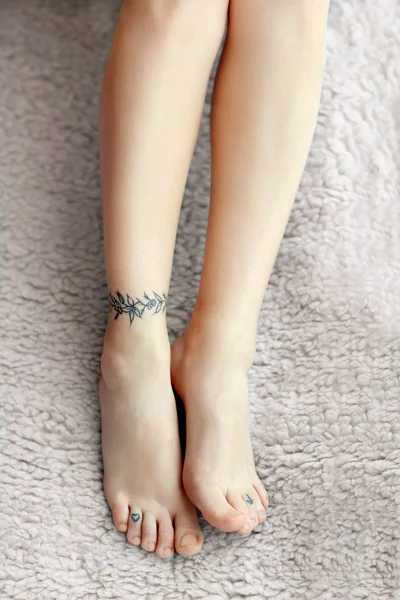 Женские ноги с татуировкой — стоковое фото