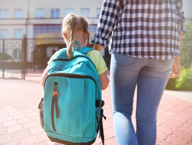 Anne kızını okula götürüyor.