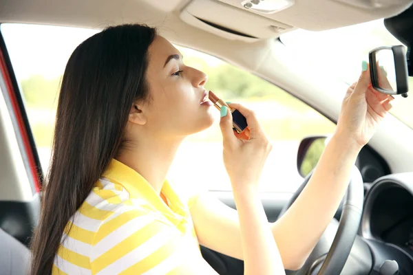 Woman applying lipstick in car — Stock Photo, Image