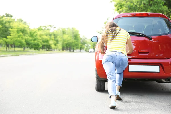 Kobieta pchania czerwony samochód — Zdjęcie stockowe