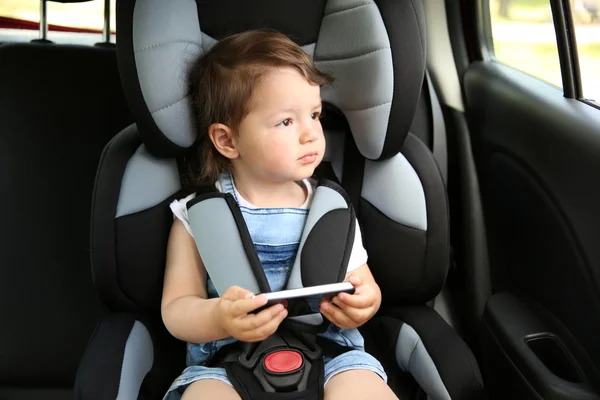 Pojken sitter i en bil i säkerhet stol — Stockfoto