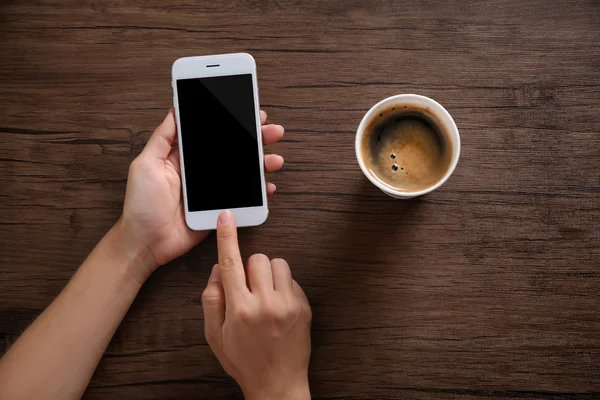 Жіночі руки з мобільним телефоном і чашкою — стокове фото