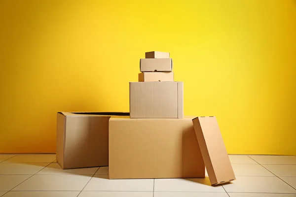 Carton boxes near yellow wall — Stock Photo, Image