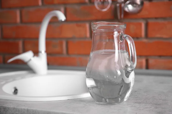 Cruche en verre d'eau et évier blanc — Photo