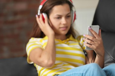 Kız akıllı telefon ve kulaklık ile müzik dinlemek