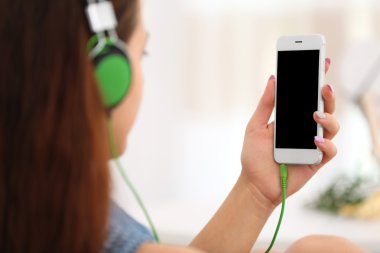 Kız akıllı telefon ve kulaklık ile müzik dinlemek