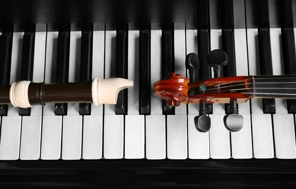 Flute and violin neck on piano keys — Stock Photo, Image