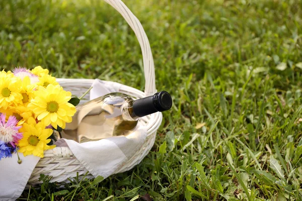 Bottiglia di vino con fiori nel cestino — Foto Stock