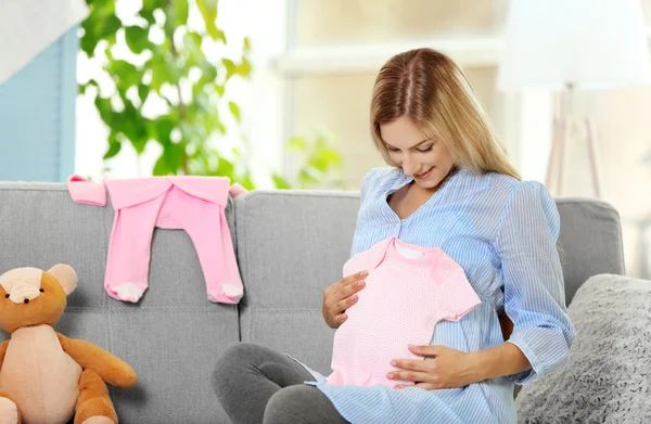 Mulher grávida com roupas de bebê — Fotografia de Stock