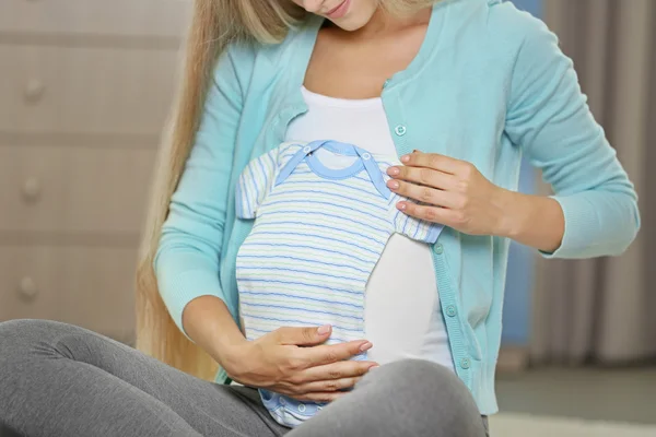 Mulher grávida com roupas de bebê — Fotografia de Stock