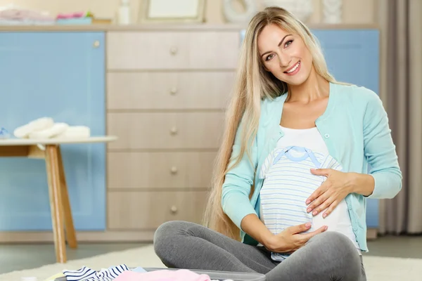 Έγκυος γυναίκα με τα ρούχα του μωρού — Φωτογραφία Αρχείου