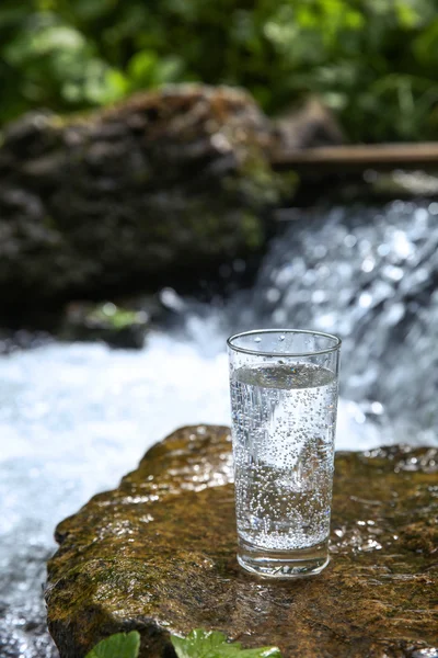 Cup of water on small waterfall — Stock Photo, Image