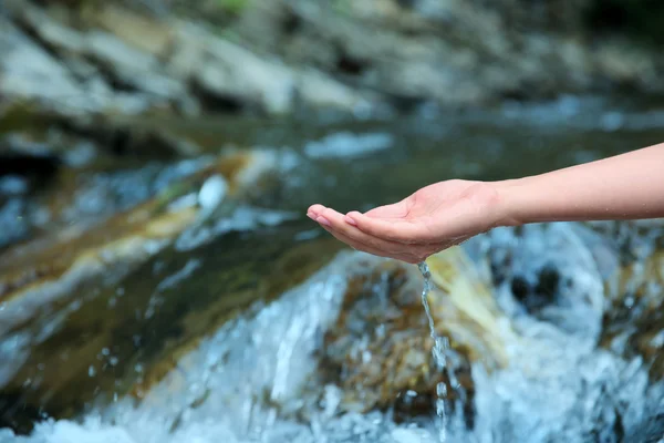 Female hand in water stream