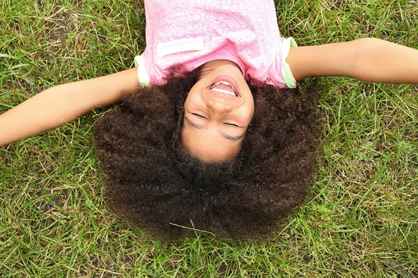 Afro-americana menina deitada na grama — Fotografia de Stock