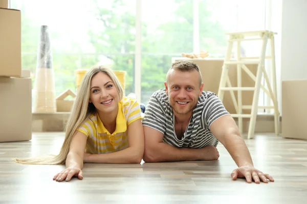 Beautiful couple lying on wooden floor — Stock Photo, Image