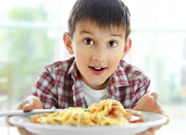 キッチンでスパゲティを食べるかわいい男の子 — ストック写真