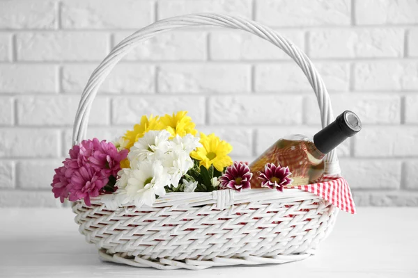 Wine bottle with flowers in basket — Stock Photo, Image