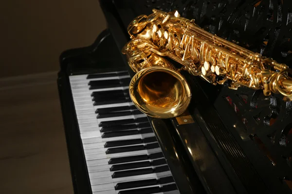 Саксофон, лежащий на пианино — стоковое фото