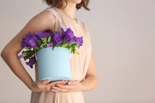 Vrouw met doos met paarse bellflowers — Stockfoto