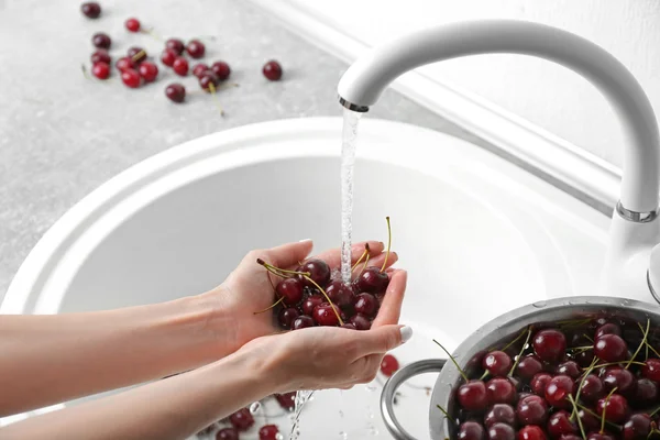 Vrouwelijke handen wassen kersen — Stockfoto