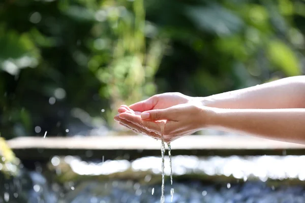 Water dropping from woman's hands — Stock Photo, Image